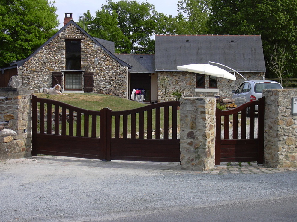 Esempio della facciata di una casa piccola beige country a un piano con rivestimento in pietra e tetto a capanna