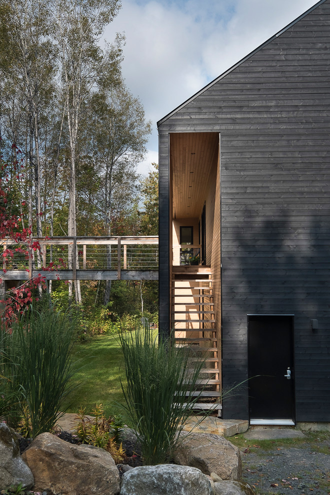 Стильный дизайн: одноэтажный, деревянный, черный частный загородный дом в стиле модернизм с металлической крышей - последний тренд
