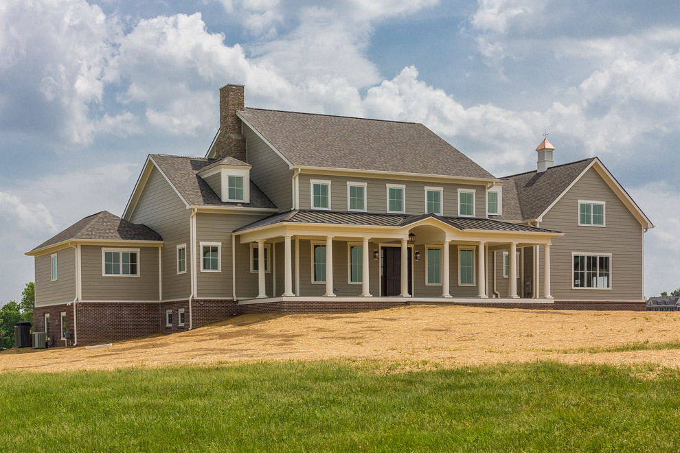Immagine della facciata di una casa grande beige country a due piani con rivestimento con lastre in cemento