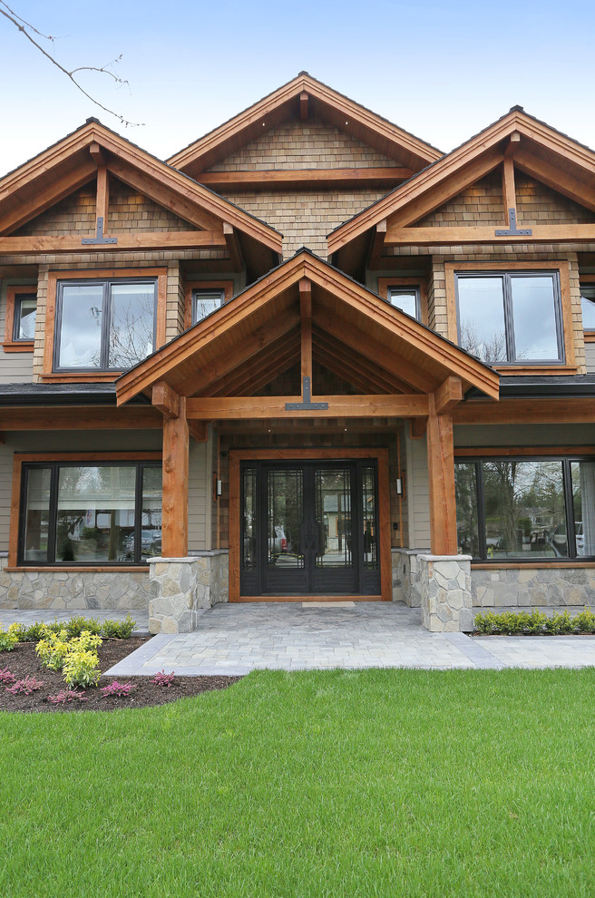 Ejemplo de fachada de casa marrón de estilo americano grande de dos plantas con revestimientos combinados, tejado a dos aguas y tejado de teja de madera