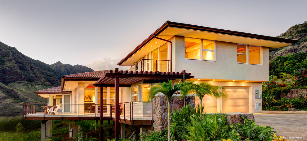 Foto della facciata di una casa beige tropicale a due piani con rivestimento in stucco