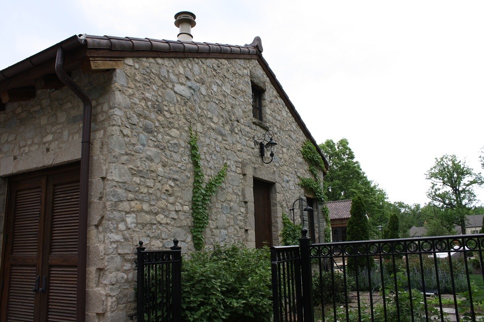 Imagen de fachada de casa gris mediterránea de una planta con revestimiento de piedra y tejado de teja de barro