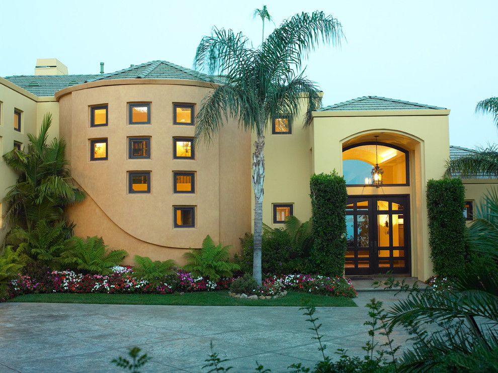Zweistöckiges Mediterranes Haus mit Putzfassade und gelber Fassadenfarbe in Los Angeles