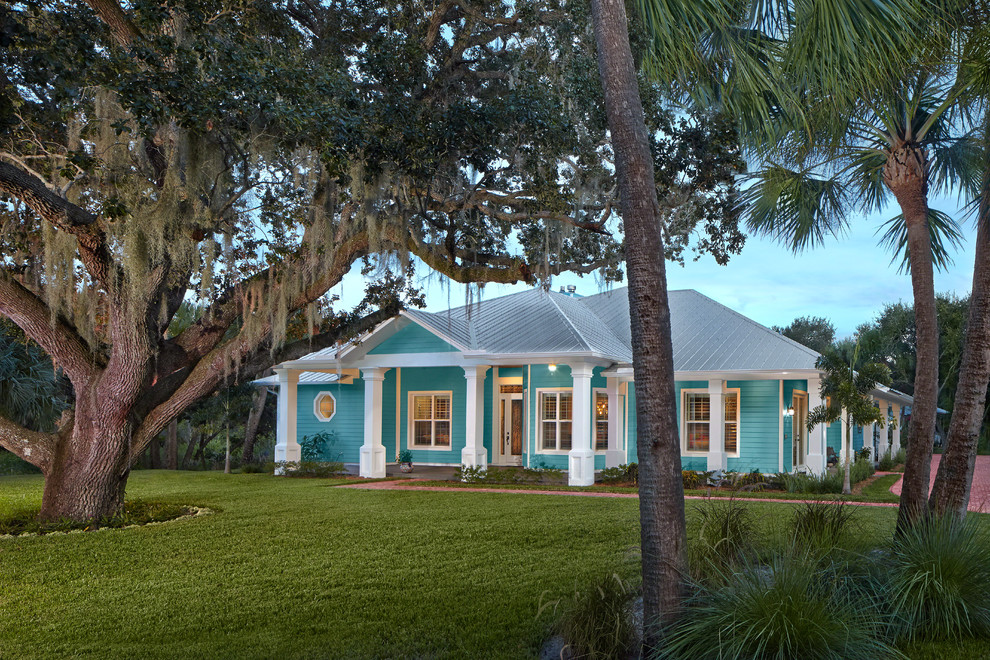Large island style blue one-story wood exterior home photo in Miami with a hip roof