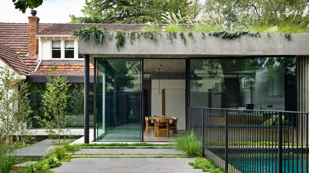 メルボルンにあるラグジュアリーなおしゃれな家の外観 (コンクリートサイディング、緑化屋根) の写真