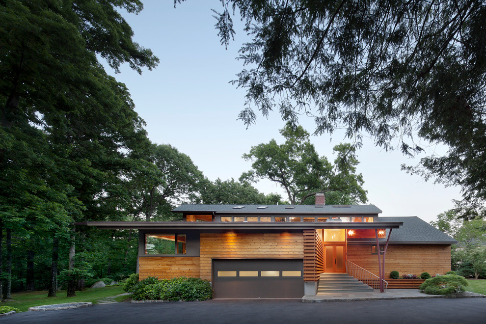 Idée de décoration pour une grande façade de maison marron design en bois à un étage avec un toit à deux pans.