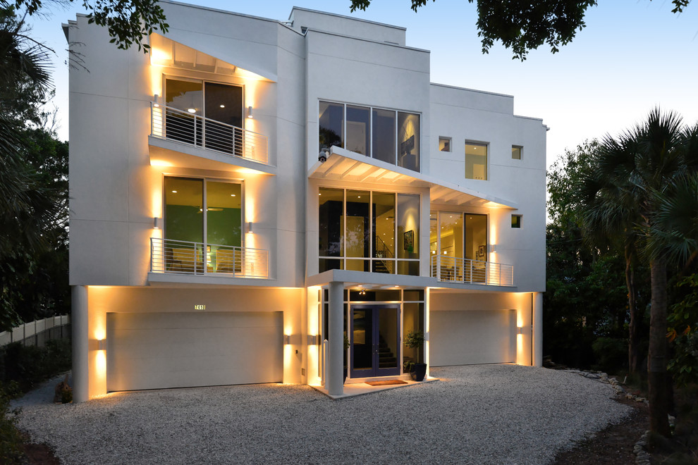 Пример оригинального дизайна: большой, трехэтажный, белый дом в стиле модернизм с облицовкой из цементной штукатурки
