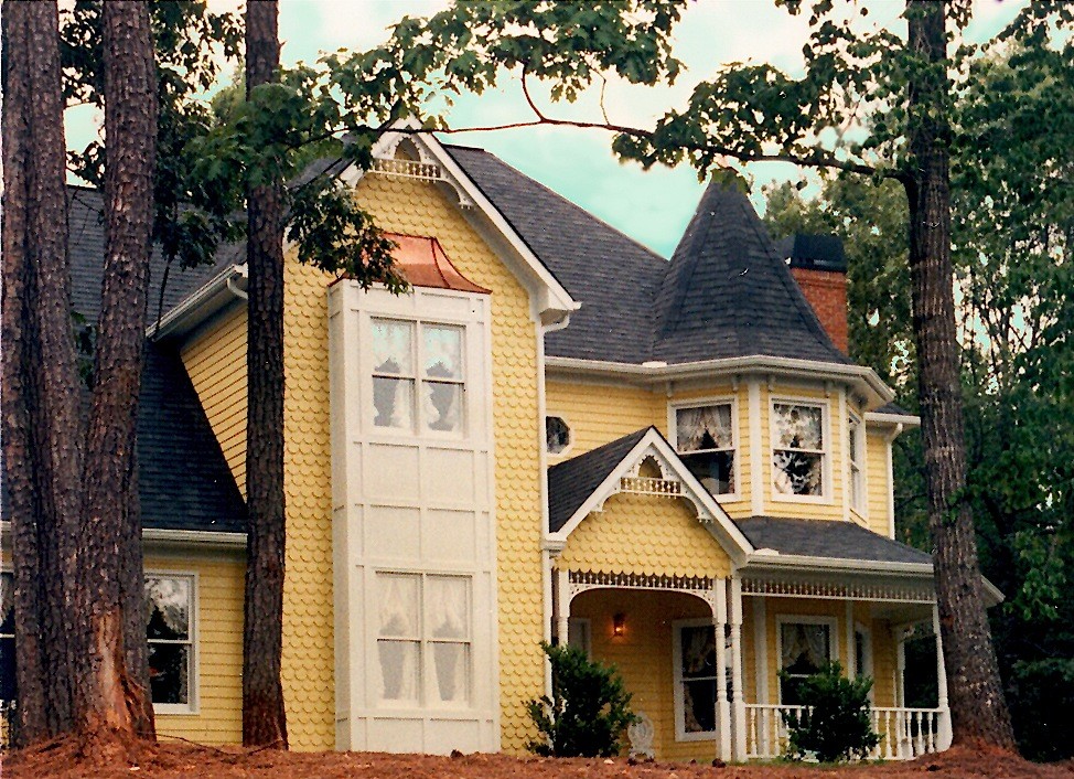 Exempel på ett mellanstort klassiskt gult trähus, med två våningar och sadeltak