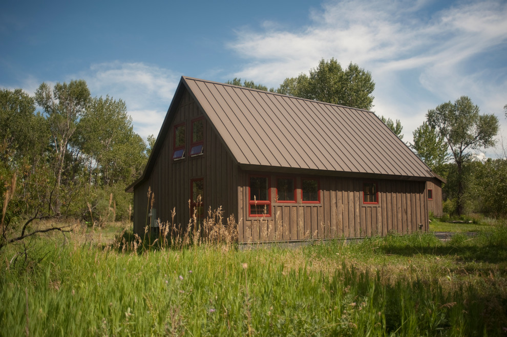 Immagine della facciata di una casa piccola marrone rustica a un piano con rivestimento in legno e tetto a capanna