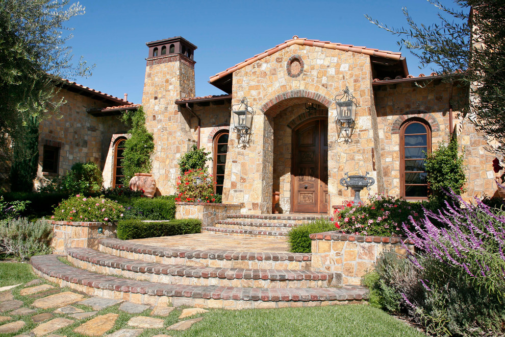 Design ideas for a mediterranean house exterior in Orange County with stone cladding.