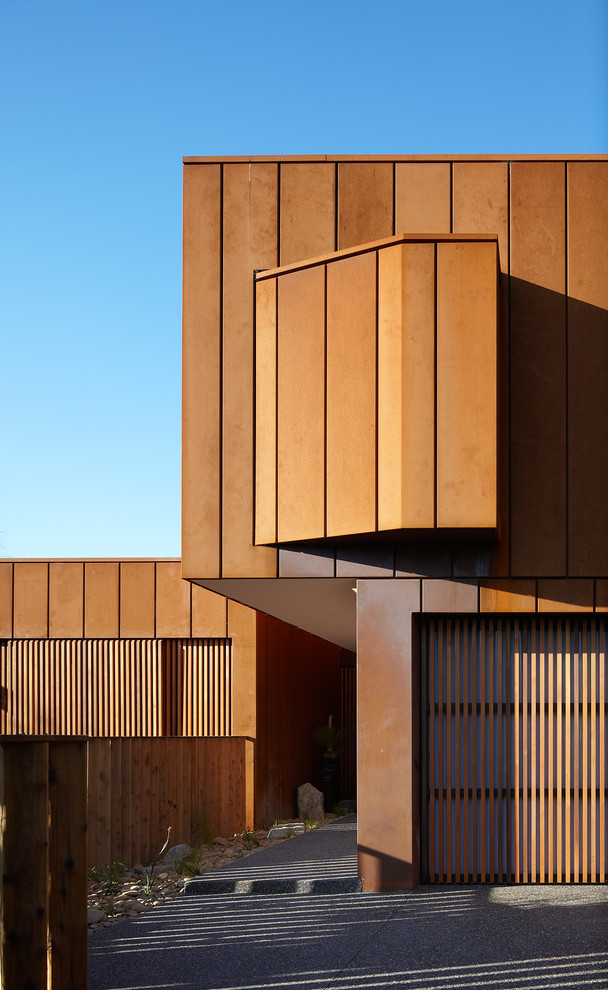 На фото: двухэтажный, коричневый дом в современном стиле с плоской крышей с