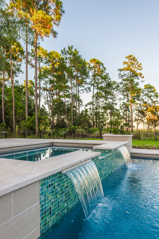 Diseño de piscina con fuente alargada tradicional renovada grande rectangular en patio trasero con adoquines de hormigón