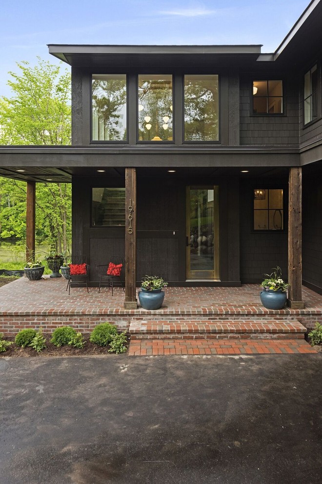 Photo of a large and black traditional two floor detached house in Minneapolis with wood cladding, a shingle roof and a flat roof.