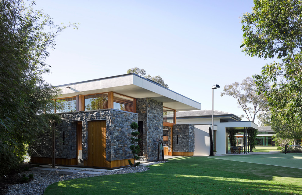 На фото: одноэтажный, серый дом в стиле модернизм с облицовкой из камня и плоской крышей с