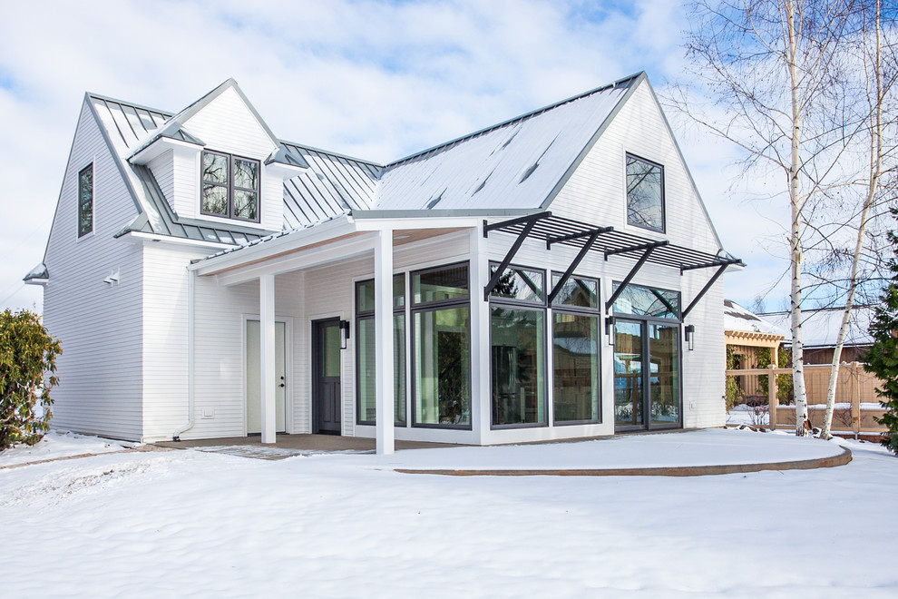 Immagine della facciata di una casa piccola bianca country a due piani con rivestimento con lastre in cemento e tetto a capanna