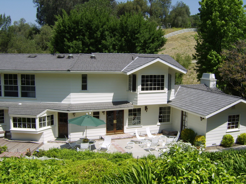 Exemple d'une grande façade de maison blanche nature en béton à un étage avec un toit à quatre pans.