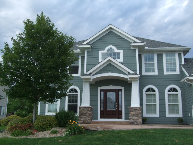 Cette photo montre une façade de maison verte chic en panneau de béton fibré de taille moyenne et à un étage avec un toit à quatre pans.