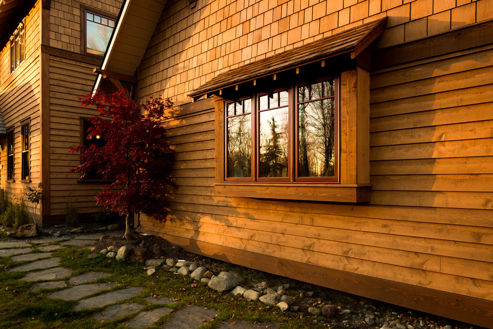 Réalisation d'une grande façade de maison marron craftsman en bois à un étage avec un toit à deux pans.
