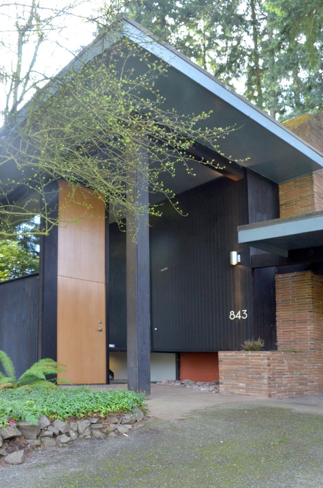 Esempio della facciata di una casa moderna a un piano di medie dimensioni con rivestimento in legno e abbinamento di colori