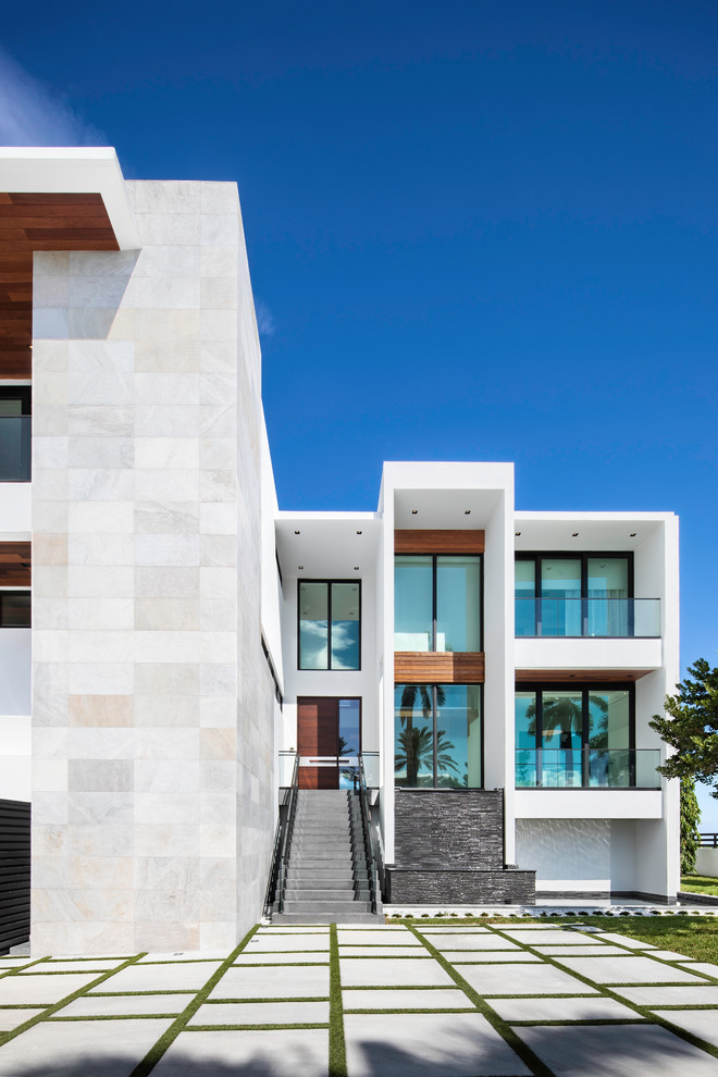 Идея дизайна: большой, трехэтажный, белый частный загородный дом в современном стиле с облицовкой из камня, плоской крышей и крышей из смешанных материалов