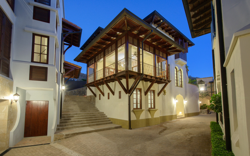Réalisation d'une grande façade de maison beige ethnique en béton à deux étages et plus avec un toit à quatre pans et un toit en tuile.
