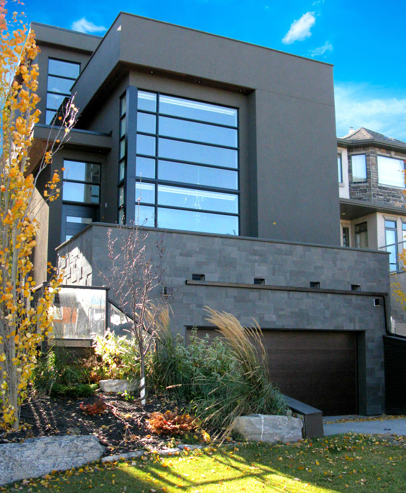 Inspiration for a black modern house exterior in Calgary with stone cladding and a flat roof.