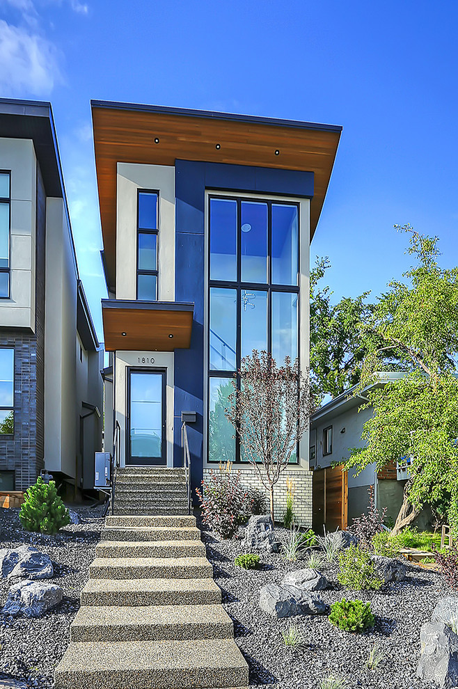 This is an example of a small and blue contemporary two floor brick house exterior in Calgary with a lean-to roof.