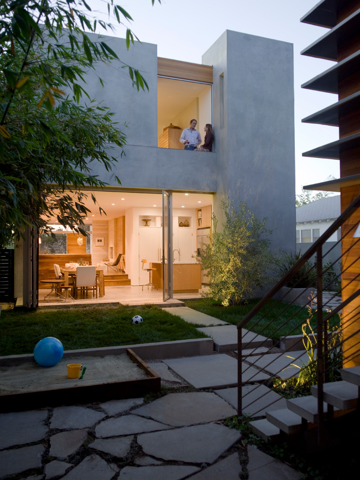 Idée de décoration pour une façade de maison grise minimaliste en stuc à un étage et de taille moyenne avec un toit plat.