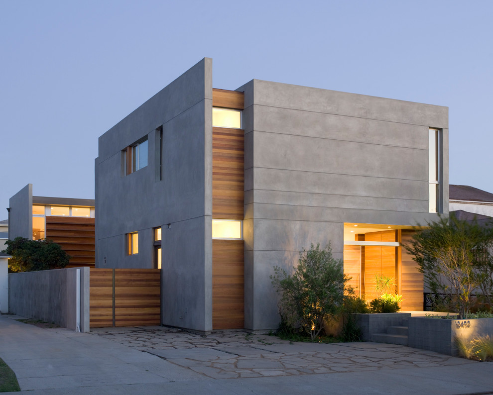 Réalisation d'une façade de maison grise minimaliste en stuc de taille moyenne et à un étage avec un toit plat.