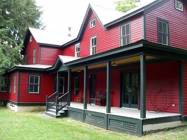 На фото: большой, двухэтажный, красный дом в стиле кантри с облицовкой из винила и односкатной крышей с