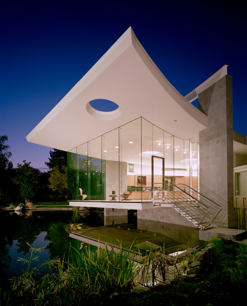 Cette photo montre une grande façade de maison grise moderne en béton de plain-pied avec un toit plat.
