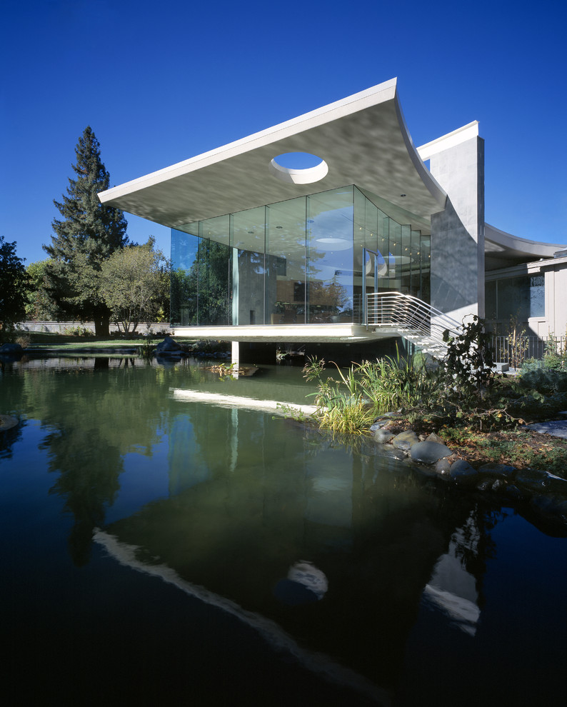 Cette image montre une grande façade de maison grise minimaliste en béton de plain-pied avec un toit plat.