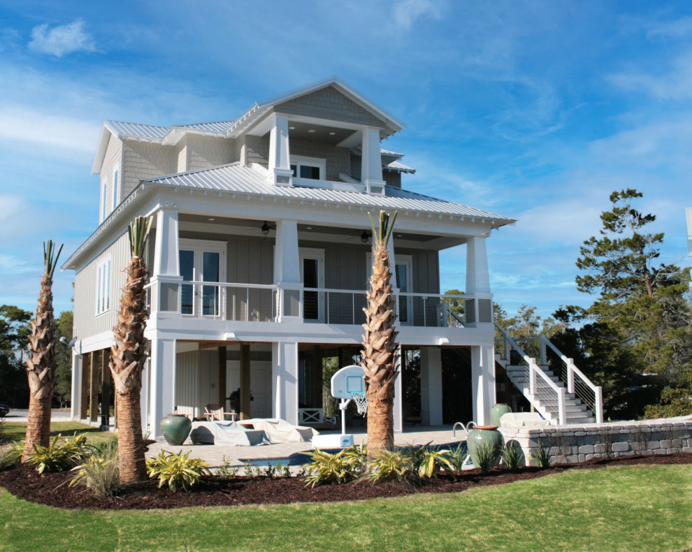 Inspiration for a gey coastal house exterior with three floors.