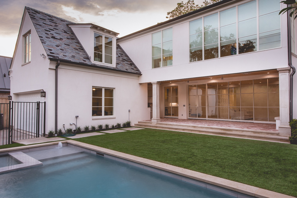 Esempio della facciata di una casa grande beige classica a due piani con rivestimento in stucco e tetto a padiglione