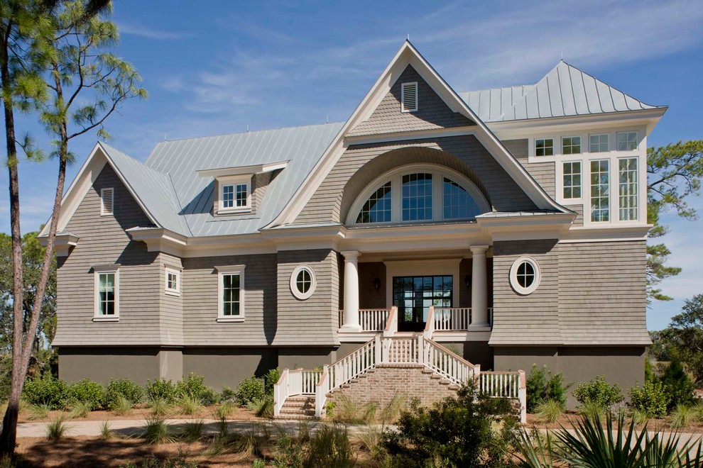 Cette photo montre une grande façade de maison grise bord de mer à un étage avec un revêtement mixte, un toit à deux pans et un toit en métal.