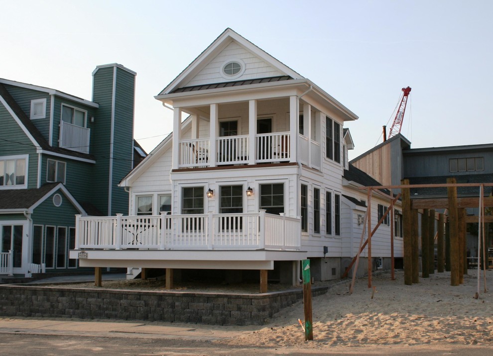 Bild på ett litet maritimt vitt hus, med två våningar, vinylfasad, sadeltak och tak i shingel