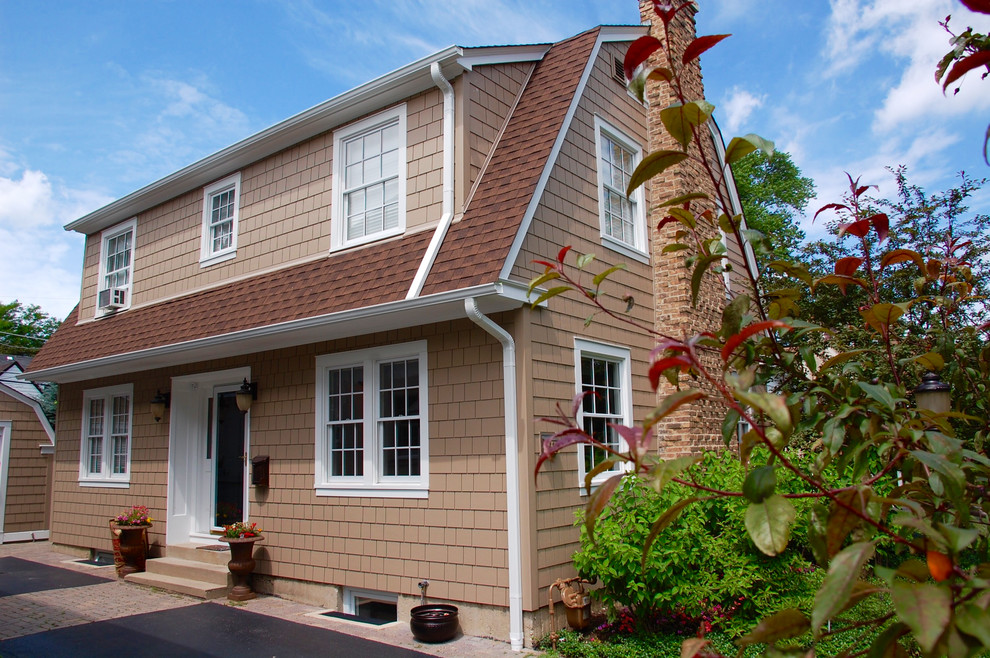 На фото: двухэтажный, коричневый дом среднего размера в классическом стиле с облицовкой из ЦСП и двускатной крышей с