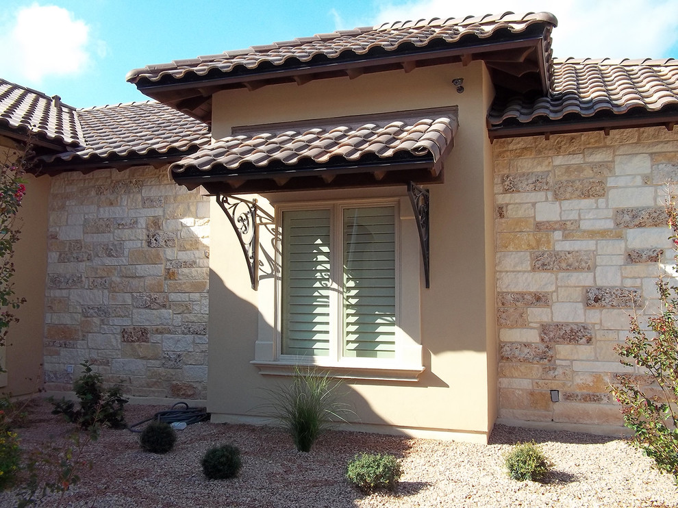 Tuscan brown one-story stone house exterior photo in Austin with a hip roof and a tile roof