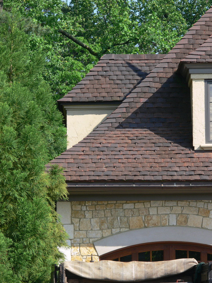 Modelo de fachada de casa beige tradicional grande de tres plantas con revestimiento de piedra, tejado a cuatro aguas y tejado de teja de barro