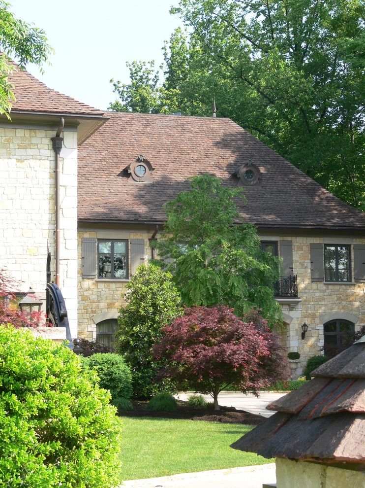 Foto della villa grande beige vittoriana a tre piani con rivestimento in pietra, tetto a padiglione e copertura in tegole