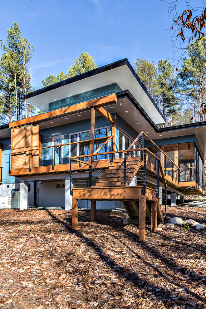 Réalisation d'une façade de maison bleue vintage en panneau de béton fibré de taille moyenne et de plain-pied avec un toit plat et un toit végétal.