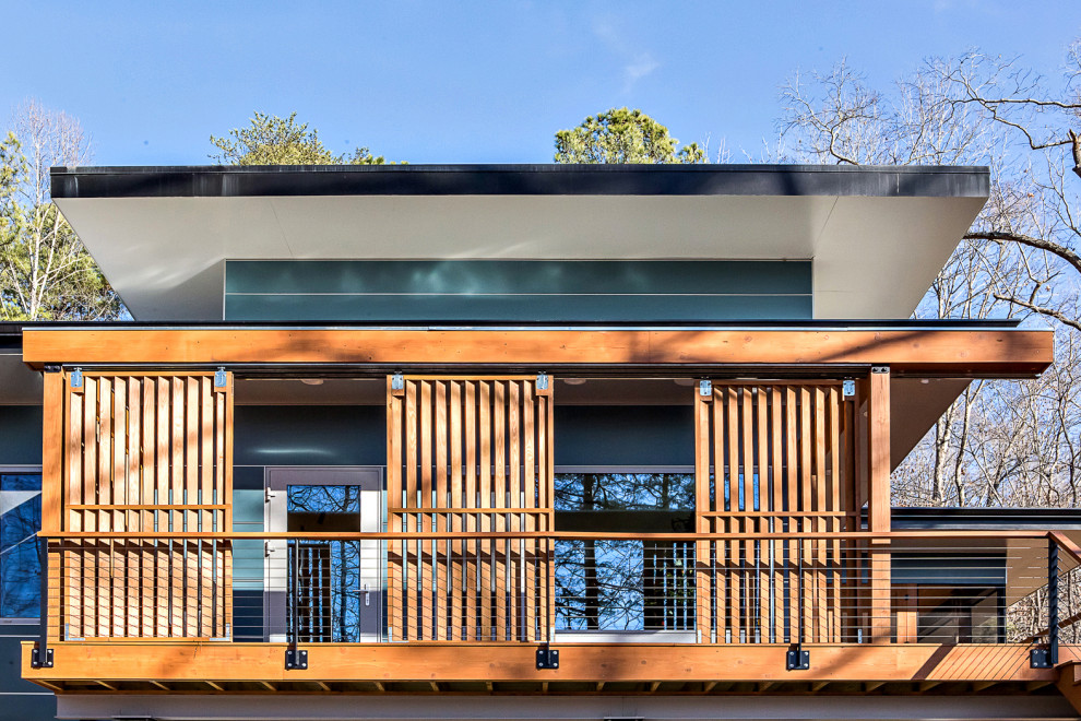Пример оригинального дизайна: одноэтажный, синий частный загородный дом среднего размера в стиле ретро с облицовкой из ЦСП, плоской крышей и зеленой крышей