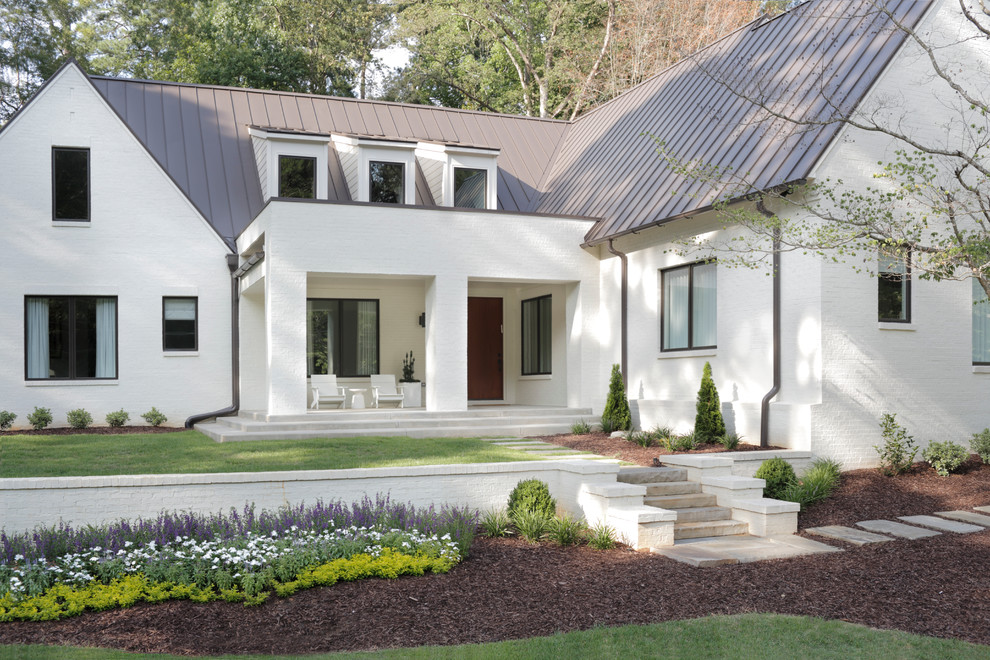 Immagine della facciata di una casa bianca classica a due piani con rivestimento in mattoni, tetto a capanna e copertura in metallo o lamiera