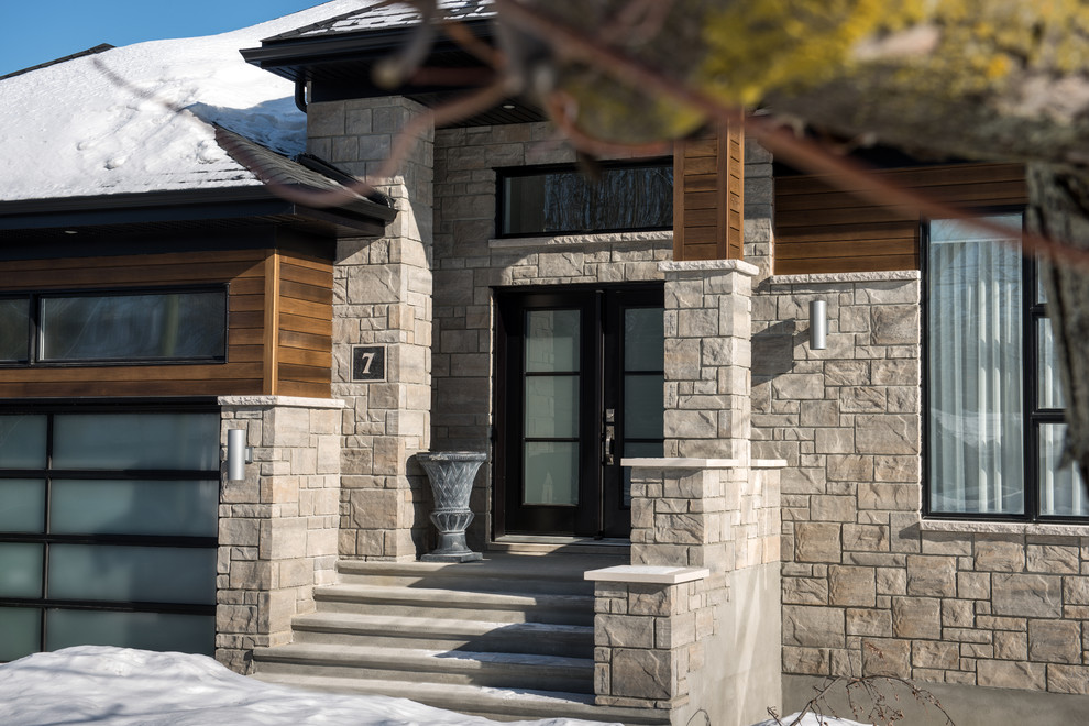 На фото: большой, двухэтажный, серый дом в стиле рустика с облицовкой из камня и полувальмовой крышей