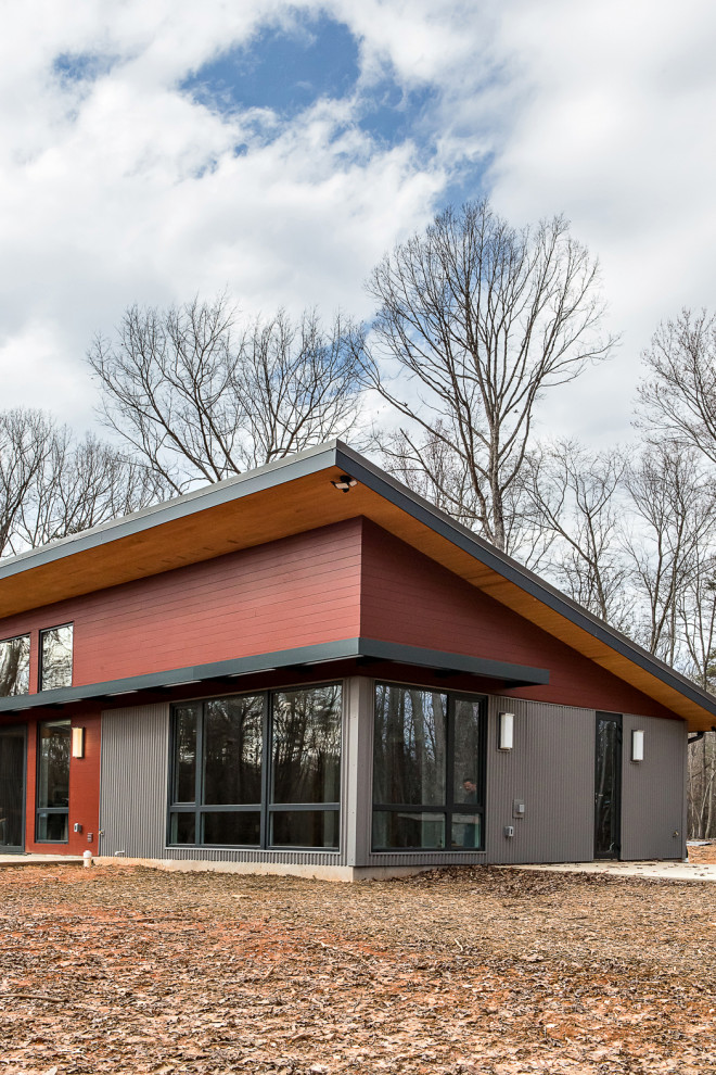Foto på ett mellanstort funkis flerfärgat hus, med allt i ett plan, blandad fasad, pulpettak och tak i metall