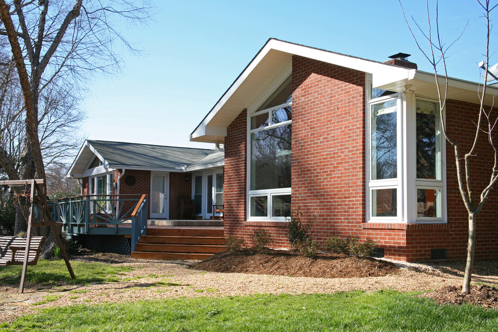 Réalisation d'une façade de maison rouge tradition en brique de taille moyenne et de plain-pied avec un toit à deux pans.