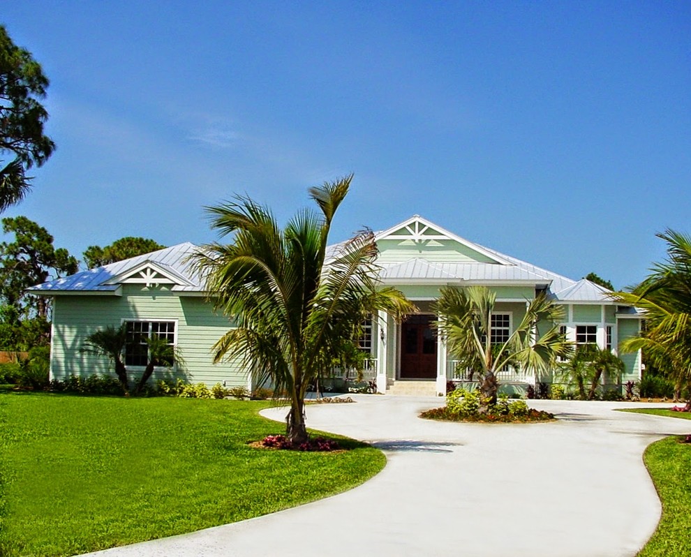 Example of a mid-sized island style green one-story wood house exterior design in Miami with a hip roof and a metal roof