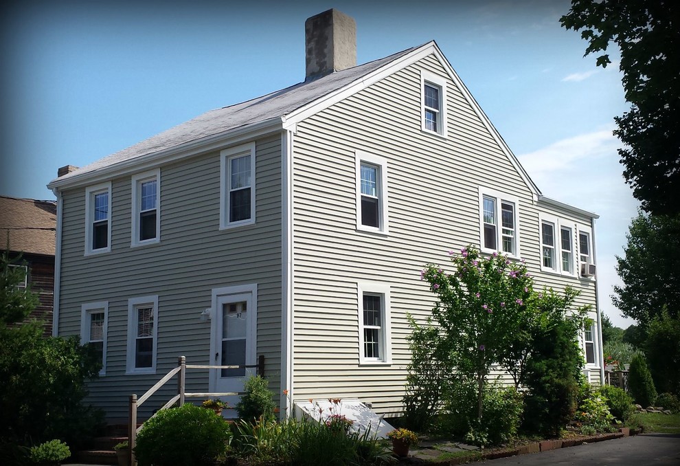 Cette photo montre une façade de maison beige chic à un étage avec un revêtement en vinyle.