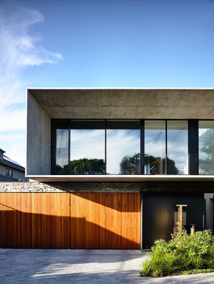 Idée de décoration pour une grande façade de maison beige design en pierre à un étage avec un toit plat et un toit mixte.
