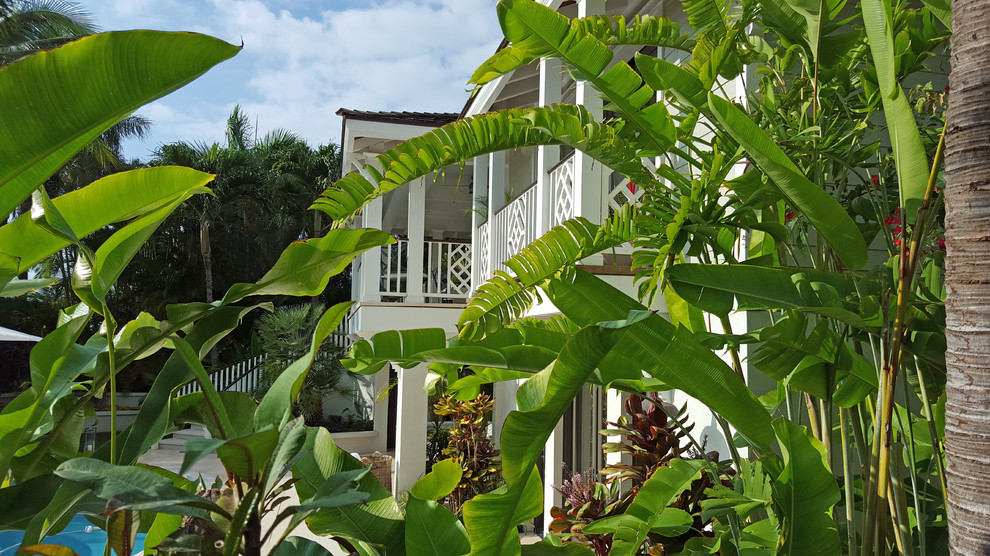 Inspiration for a mid-sized tropical white two-story vinyl exterior home remodel in Other with a hip roof